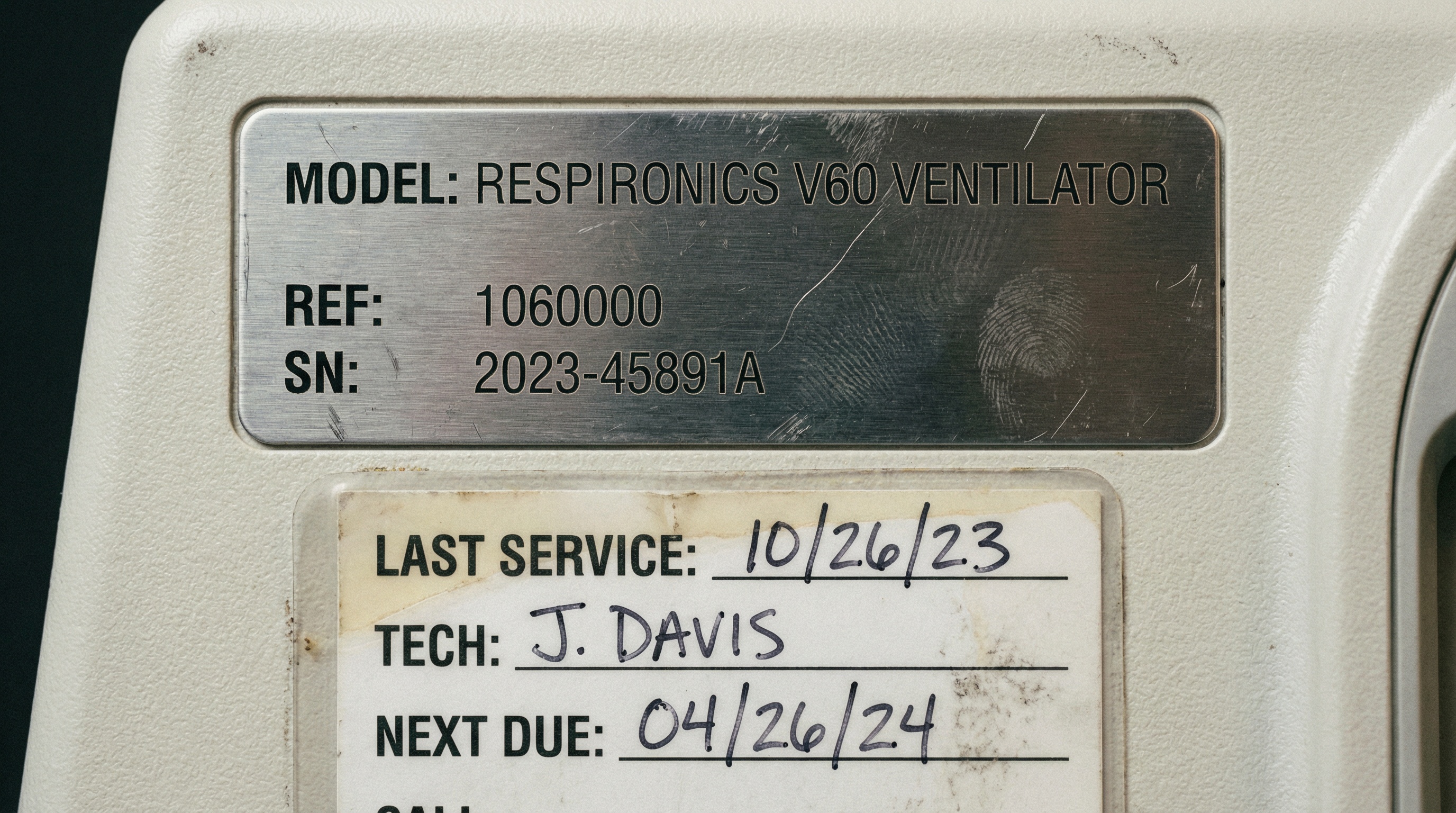 detailed close-up of medical equipment serial number plate and maintenance documentation
