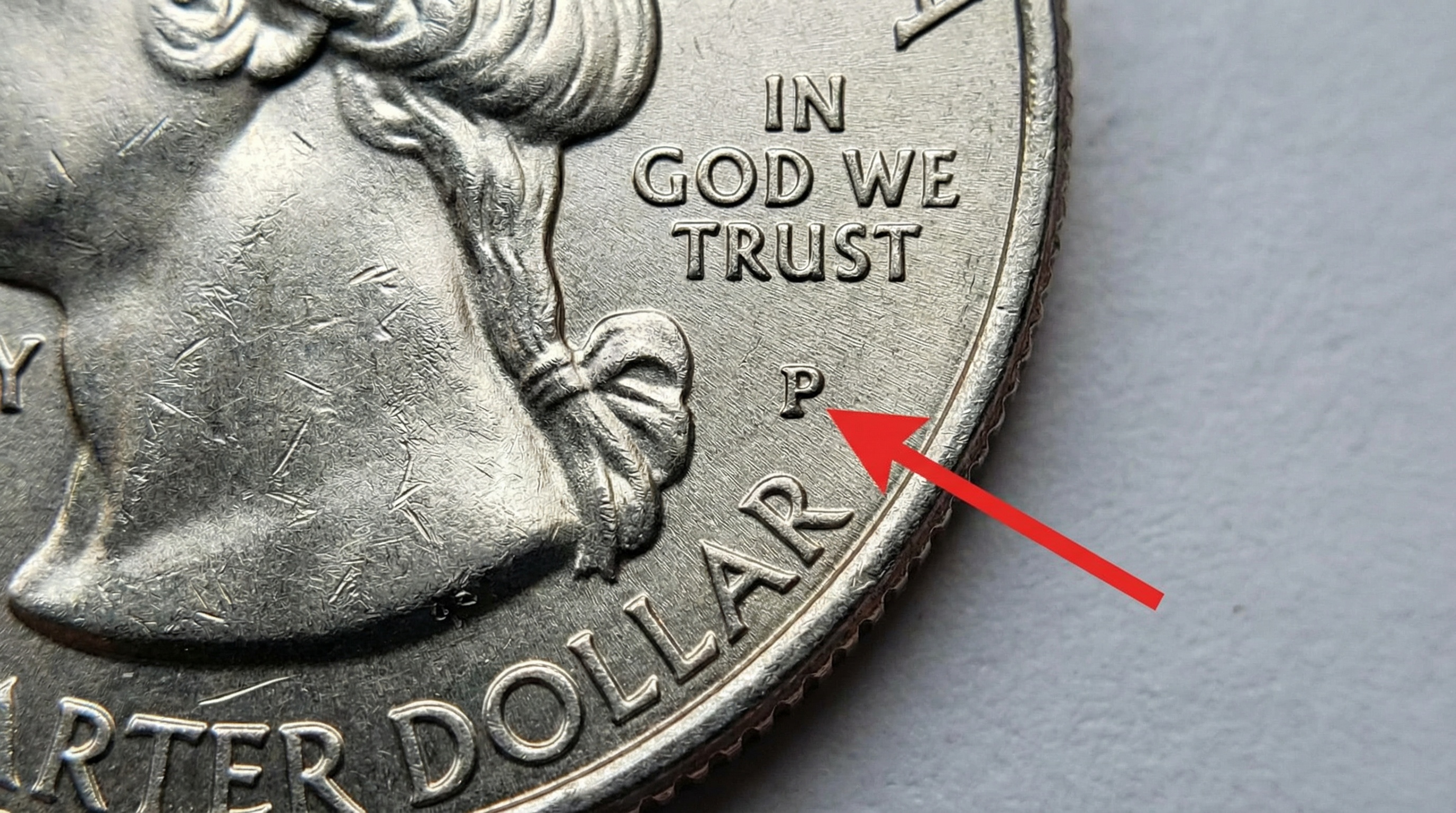 close-up of coin showing mint mark location with arrow pointing to the small letter