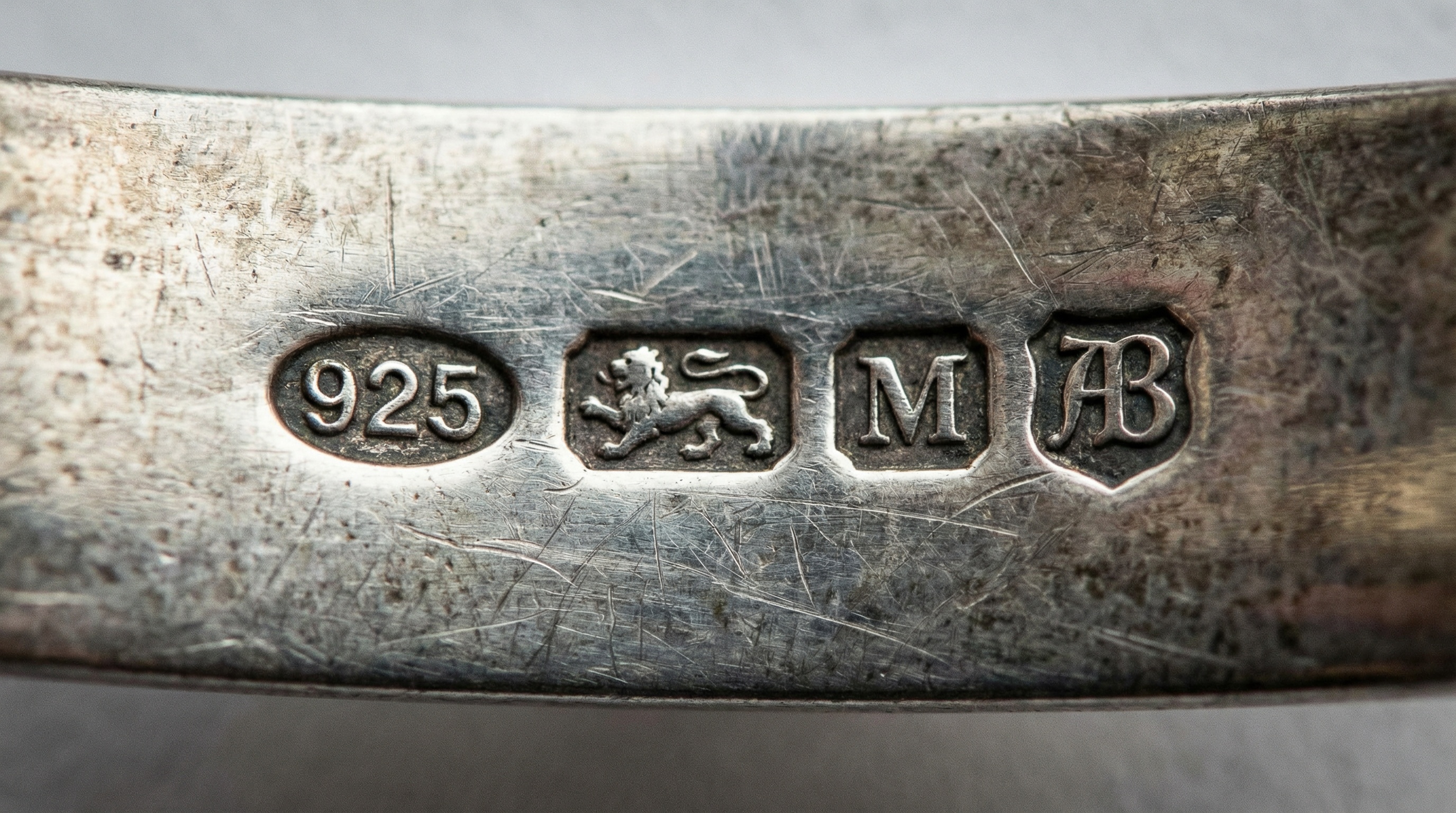 close-up of silver hallmarks showing "925" sterling mark and maker's monogram