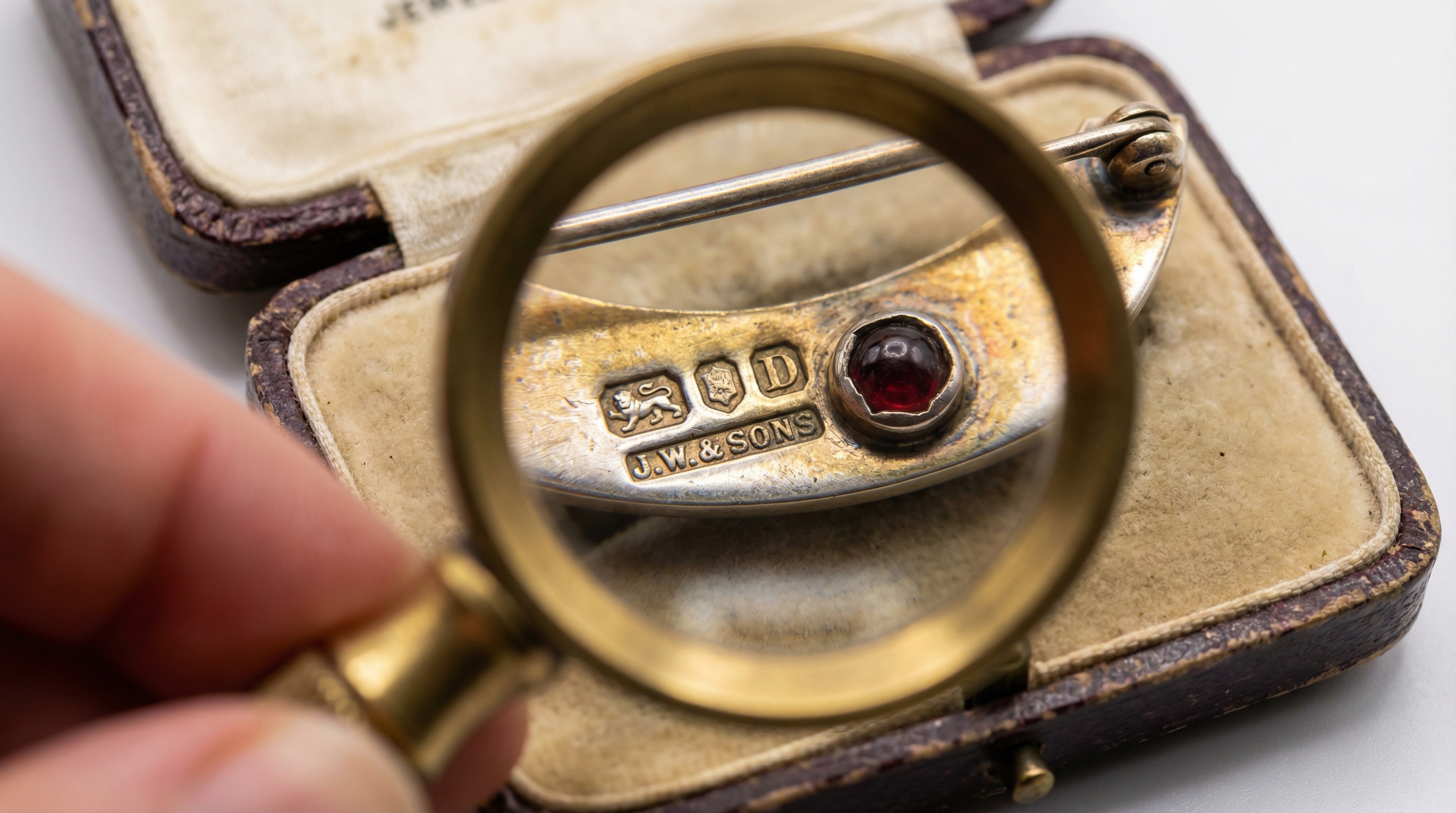 Close-up of antique jewelry showing hallmarks and maker marks under magnification